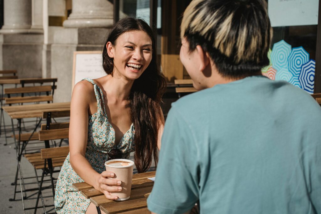 Two friends enjoying a sunny day, chatting over coffee at an outdoor cafe.